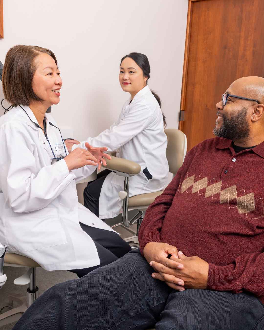 Dr. Wu in a clinical room with a patient discussing care.
